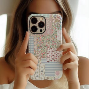 May include: A white iPhone case with a patchwork design featuring floral and geometric patterns in shades of pink, blue, and green.