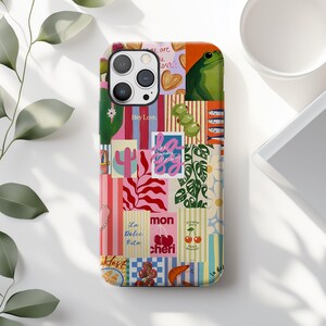 May include: A phone case featuring a vibrant collage of illustrations including a green frog, olives, cherries, cacti, and various text elements like Hey Love, La Dolce Vita, and La Sunday Morning, arranged in a colorful, multi-patterned rectangular grid.