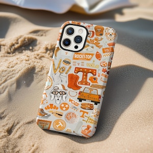 May include: A white and orange phone case featuring various Tennessee-themed graphics. The design includes the letter "T", a dog wearing glasses, a truck, and the text "ROCKY-TOP". The case is on a sandy surface.