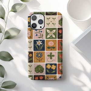 May include: A rectangular phone case featuring a grid pattern of various botanical illustrations. Each square contains a different plant, flower, or leaf design in colors including mustard yellow, sage green, navy blue, pink, and white on a cream background.