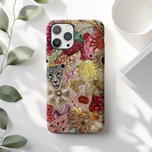 May include: A colorful phone case with a beaded design featuring a variety of motifs, including a heart, a sun, a lemon, and a leopard print. The case is designed for an iPhone with a camera lens cutout.