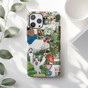 May include: A white iPhone case with a colorful collage of images, including a cat, a dragonfly, strawberries, and Japanese text. The case has a clear camera lens cutout.