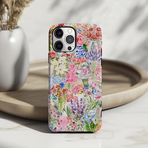 May include: A floral phone case featuring a collage of watercolor flowers in various colors, including pink, red, purple, and blue. The design includes bouquets of lavender, roses, and other blooms, with a white background. The case has a glossy finish.