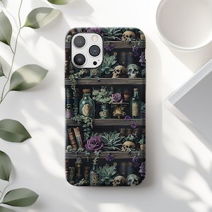 May include: A phone case featuring a dark, gothic design. The case displays a bookshelf filled with skulls, bottles, books, and purple flowers. The overall aesthetic is reminiscent of a witch's apothecary or a spooky library.