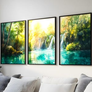 Puede incluir: Tres pinturas de acuarela enmarcadas que representan un exuberante bosque verde con una cascada que cae en una piscina turquesa. Las pinturas están dispuestas en una fila en una pared blanca.