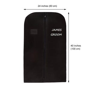 Op de afbeelding: Zwarte kledingzak met rits en een wit label met de tekst "JAMES GROOM". De zak is 60 cm bij 100 cm.