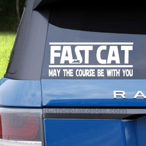 May include: A blue car with a white vinyl sticker that reads "Fast Cat May the Course Be With You" on the back window. The car has a black trim and a "Range" emblem on the back.