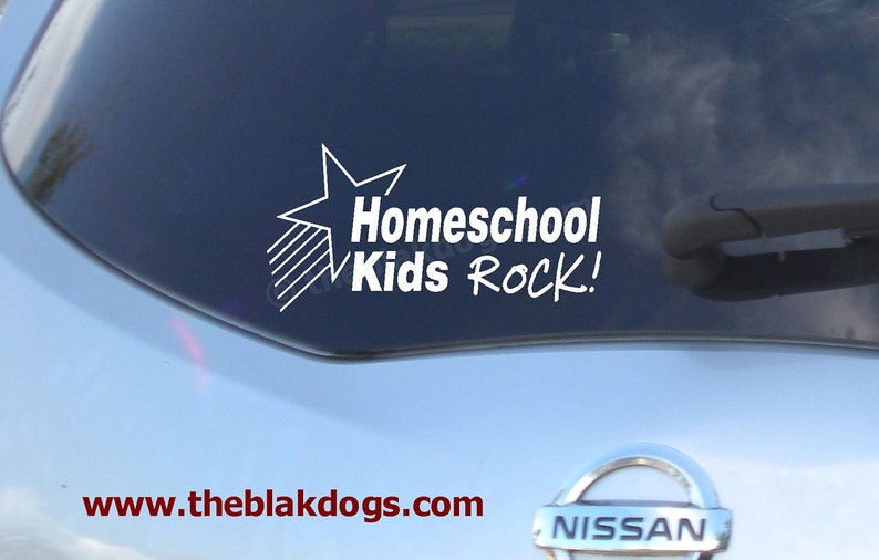 May include: A white vinyl sticker on a blue car window with a star and the text "Homeschool Kids Rock!"