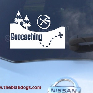 May include: White vinyl decal with a compass, trees, and the text "Geocaching" on a blue car window. The decal also includes a dotted line and a plus sign.