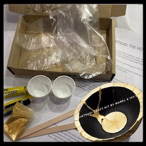 Puede incluir: Kit de artesanía Kintsugi con un cuenco de cerámica negro y dorado, dos pequeñas tazas blancas, dos tubos de resina, una pequeña bolsa de polvo dorado y dos palitos de madera. El kit incluye instrucciones para reparar la cerámica rota con oro.