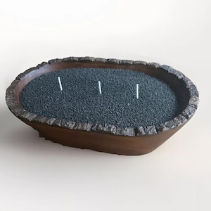 May include: A wooden bowl candle with three wicks and black wax. The bowl is shaped like a tree trunk and has a rough texture.