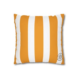 Puede incluir: Una almohada de rayas amarillas y blancas con un pequeño logotipo negro que dice "House of Champagne" en un círculo.