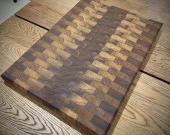May include: A large, rectangular cutting board made of dark wood with a checkered pattern. The board is made of different shades of brown wood, creating a unique and rustic look.