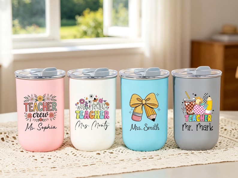 May include: Four stainless steel tumblers with lids in pink, white, light blue, and gray. Each features colorful teacher-themed graphics and names: Teacher crew Ms. Sophia, Teacher Mrs. Monty, Mrs. Smith with a pencil bow, and Teacher Mr. Mark.