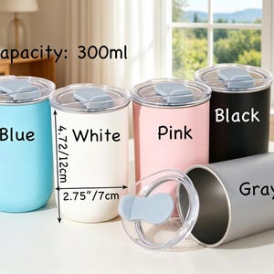 May include: Five cylindrical tumblers with 300ml capacity, each featuring a clear lid with a light blue tab. Colors include blue, white, pink, black, and gray. The white tumbler measures 4.72 inches in height and 2.75 inches in diameter.