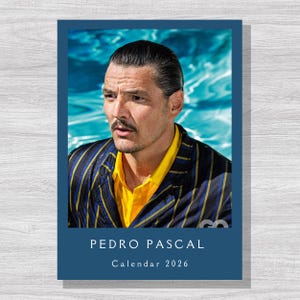 Peut inclure: Calendrier 2026 avec un portrait de Pedro Pascal. Il porte une chemise jaune et un blazer rayé bleu marine et jaune. Le calendrier est intitulé "Calendar 2026" et comprend le logo GQ.