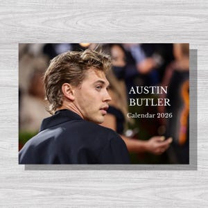Op de afbeelding: Een kalender met een foto van Austin Butler. De tekst "AUSTIN BUTLER Calendar 2026" staat in het wit. De achtergrond is een wazige afbeelding van een menigte.