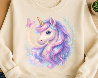 May include: A cream-colored sweatshirt with a cartoon unicorn graphic. The unicorn has a pink and blue mane and tail, and is holding a crescent moon in its mouth. There is a small pink butterfly flying near the unicorn's head.