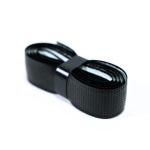 May include: Black overgrip tape for racquet sports, featuring a textured surface with small holes. The tape is rolled up and secured with a black band.