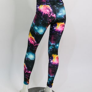 Puede incluir: Leggings negros con estampado de galaxia que presenta nebulosas rosas, azules y amarillas sobre un fondo oscuro.