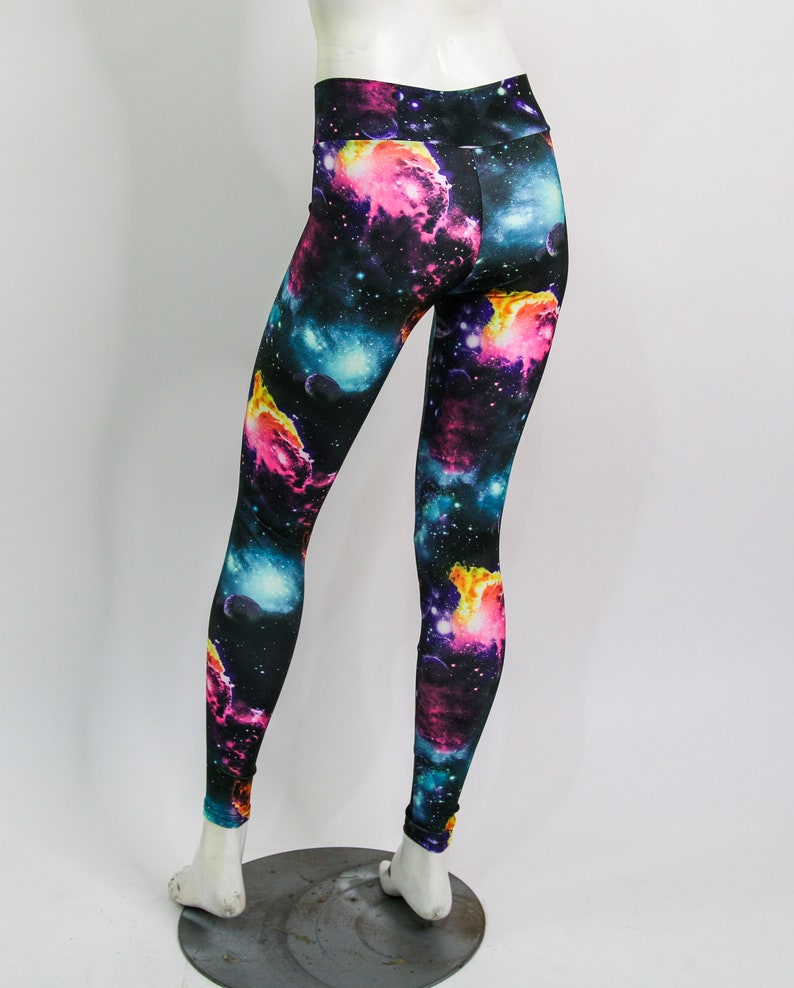 Puede incluir: Leggings negros con estampado de galaxia que presenta nebulosas rosas, azules y amarillas sobre un fondo oscuro.