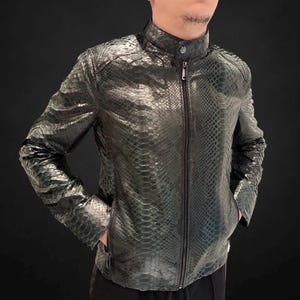 May include: A dark green leather jacket with a snakeskin pattern. The jacket has a stand-up collar, a front zipper, and two side pockets. The jacket is a stylish outerwear piece.