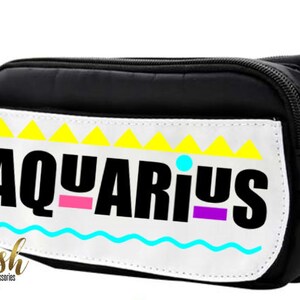 May include: Black fanny pack with a white patch that says "AQUARIUS" in black letters with pink, purple, and blue accents. The patch has a yellow and white geometric design.