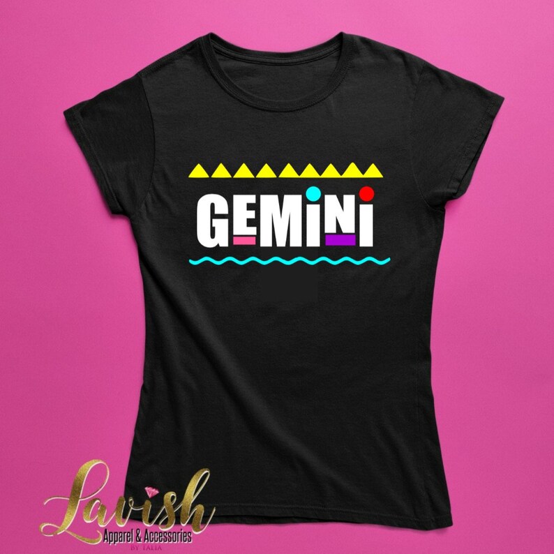 May include: Black t-shirt with a white graphic that says "GEMINI" in colorful block letters. The graphic is surrounded by yellow triangles, a blue wavy line, and colorful dots.