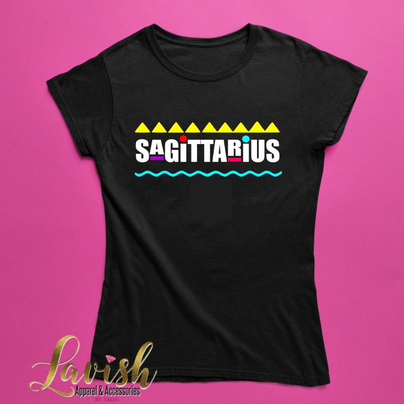 May include: Black t-shirt with a yellow, blue, red, and purple graphic that says "SAGITTARIUS" with a row of yellow triangles above the text and a wavy blue line below the text.