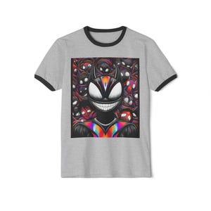 以下が含まれることがあります： 黒い襟と袖が付いたグレーのリンガーTシャツ。シャツには、虹色の胸とさまざまな顔の背景を持つ、笑顔の角のある人物のカラフルなグラフィックが描かれています。