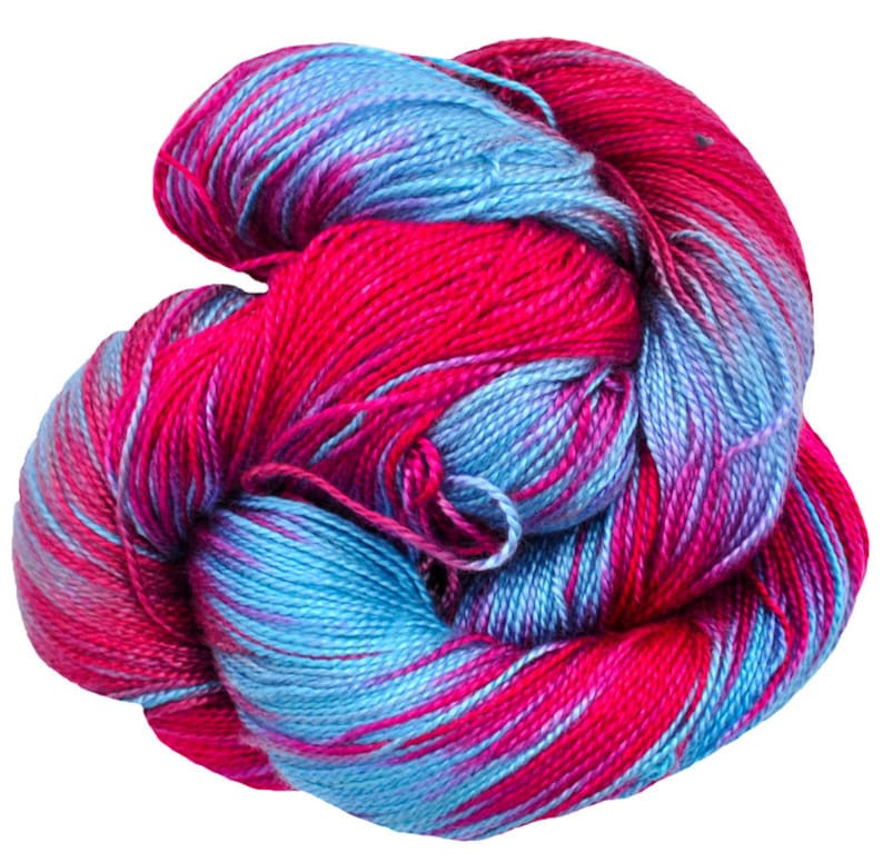 Puede incluir: Un ovillo de lana colorida en tonos rosa brillante y azul claro. La lana est&aacute; bien enrollada, mostrando una mezcla de colores en las fibras. La apariencia general es suave y acogedora, adecuada para proyectos de tejido o ganchillo.