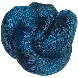 May include: Teal blue silk yarn with a subtle sheen. The yarn is twisted and knotted, showing the texture of the fibres.