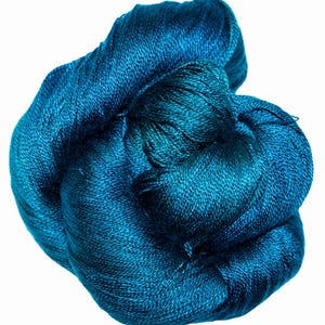 May include: A ball of teal-coloured yarn, tightly wound and textured. The yarn appears to be a luxurious fibre, possibly silk or a similar material, with a subtle sheen. The colour is a deep, rich teal, with variations in tone across the ball.