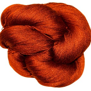 May include: A tightly wound skein of orange-red yarn, likely for knitting or crochet projects. The yarn has a fine, textured appearance, suggesting a soft and luxurious fiber. The color is a rich, warm tone, perfect for creating cozy items.