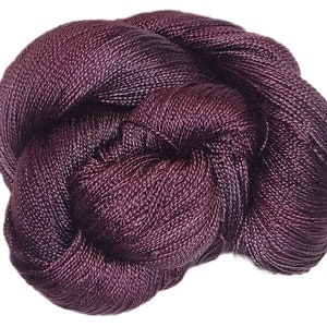 May include: A skein of deep purple silk yarn. The yarn is soft and smooth, and it has a subtle sheen.