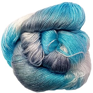 May include: A skein of yarn in shades of blue, gray, and white. The yarn is soft and silky, and it is perfect for knitting or crocheting.