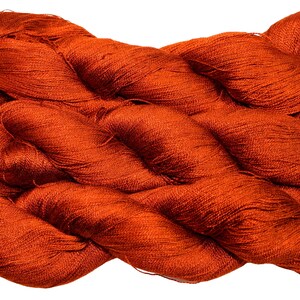 May include: A skein of vibrant orange yarn, tightly wound and textured. The yarn appears to be a fine, luxurious fiber, suitable for knitting or crochet projects. The color is a rich, warm tone, ideal for creating cozy garments or accessories.