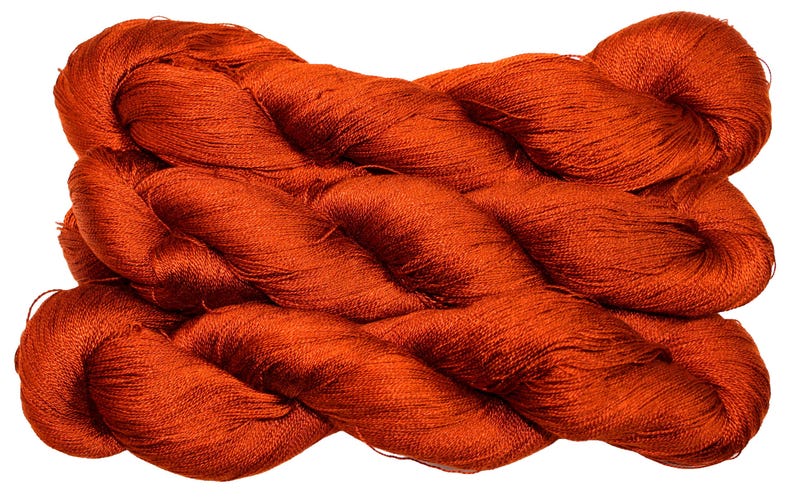 May include: A skein of vibrant orange yarn, tightly wound and textured. The yarn appears to be a fine, luxurious fiber, suitable for knitting or crochet projects. The color is a rich, warm tone, ideal for creating cozy garments or accessories.
