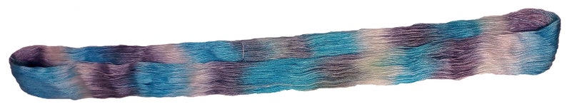 May include: A long, thin, woven strip of fabric with a gradient of blue, purple, and white colors. The fabric has a wavy texture.