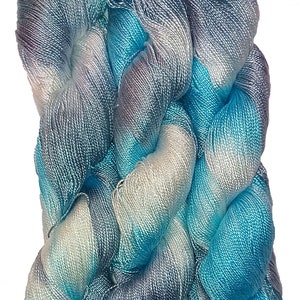 May include: A skein of blue, white, and gray yarn with a gradient color pattern. The yarn is made of silk and is soft and smooth.