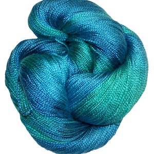 May include: A skein of teal and blue yarn with a gradient effect. The yarn is soft and smooth, and it is perfect for knitting or crocheting.