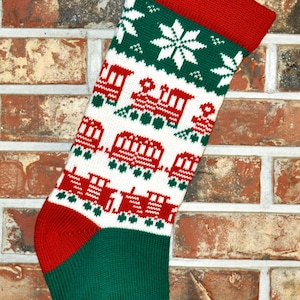 May include: A red, green, and white knitted Christmas stocking with a train pattern. The stocking has a loop at the top for hanging.