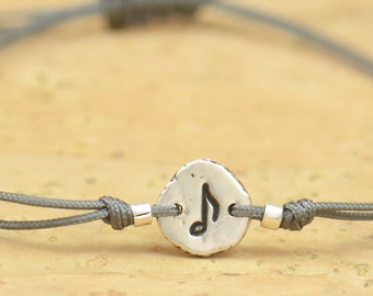 Peut inclure: Un bracelet en cordon gris avec un charme argenté en forme de note de musique.