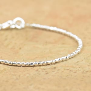 Pode incluir: Um delicado bracelete de prata feito de pequenas contas. O bracelete é simples e elegante, perfeito para o uso diário.
