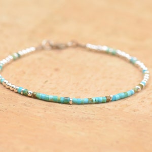 Könnte beinhalten: Ein zartes Armband aus kleinen türkisfarbenen und silbernen Perlen. Das Armband ist schlicht gehalten und wäre ein tolles Geschenk.