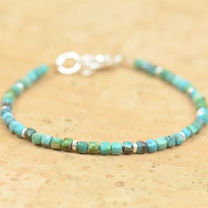 Op de afbeelding: Een turquoise edelsteen armband met zilveren kralen en een zilveren sluiting.