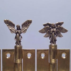 May include: Four brass door hinges arranged in a row, each featuring a unique decorative angel finial at the top. The rectangular hinge plates have pre-drilled screw holes, and the metal has a polished, reflective gold-toned finish throughout.