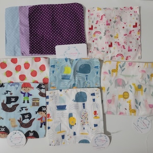 Könnte beinhalten: Sortiment von 10 Stoffquadraten mit verschiedenen bunten Mustern. Die Muster umfassen Erdbeeren, Piraten, Wale, Tiere und abstrakte Designs. Die Quadrate sind alle etwa 30 cm x 30 cm groß.