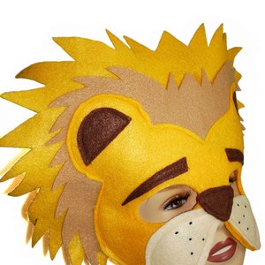 May include: A yellow felt lion mask with brown felt eyebrows, a brown nose, and white felt whiskers. The mask has a brown felt mane and a yellow felt face.