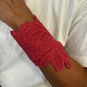 Bracciale unico nel suo genere, realizzato a mano a Firenze, Italia, in pizzo antico e tessuto rosso con bottone in metallo.